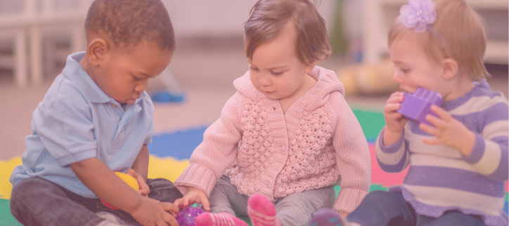 Three children playing with toys in a classroom.