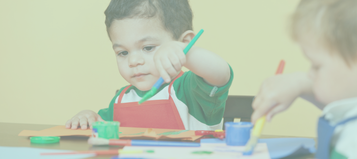 two children at a table with paintbrushes