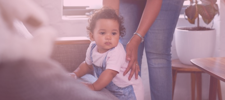 A person is holding a baby while sitting on a couch