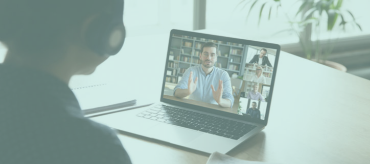 a person sitting in front of a laptop with two people on the screen