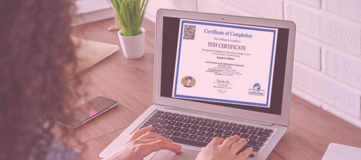 a person working on a laptop at a desk with a certificate in front of them