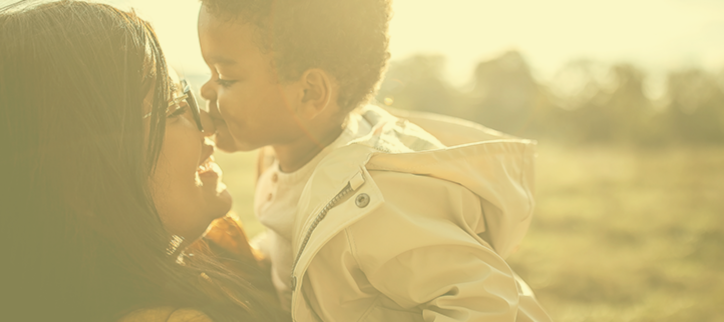 a parent kisses their child on the cheek in a field