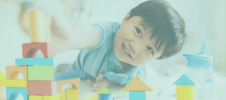 a child smiles while playing with toy blocks