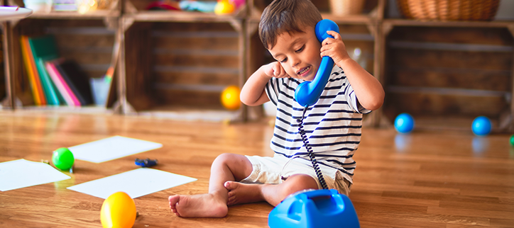 Little boy playing with a toy telephone.