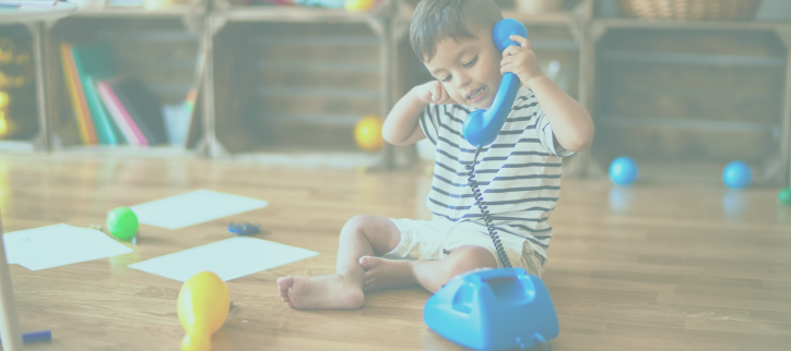 a child sitting on the floor talking on the phone