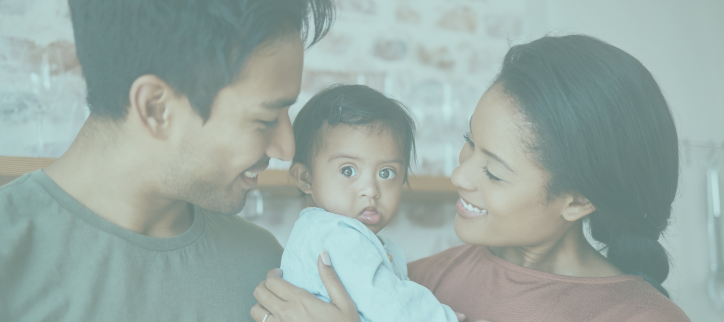 Two people holding a baby while looking at each other