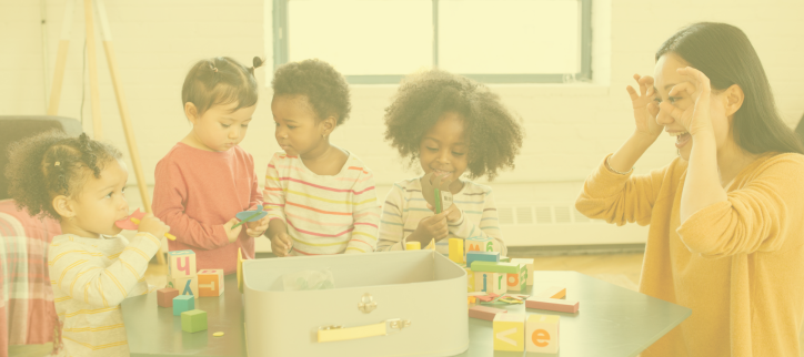 a teacher sitting at a table with a group of children