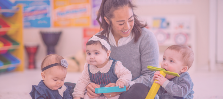 Teacher interacting with infant students and playing with blocks.