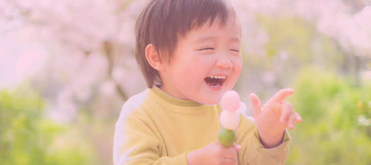 toddler laughing holding a flower outside